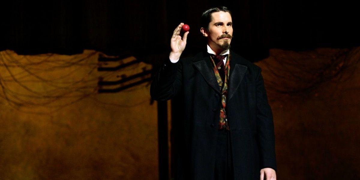 Alfred Borden hold an apple up on stage in The Prestige.