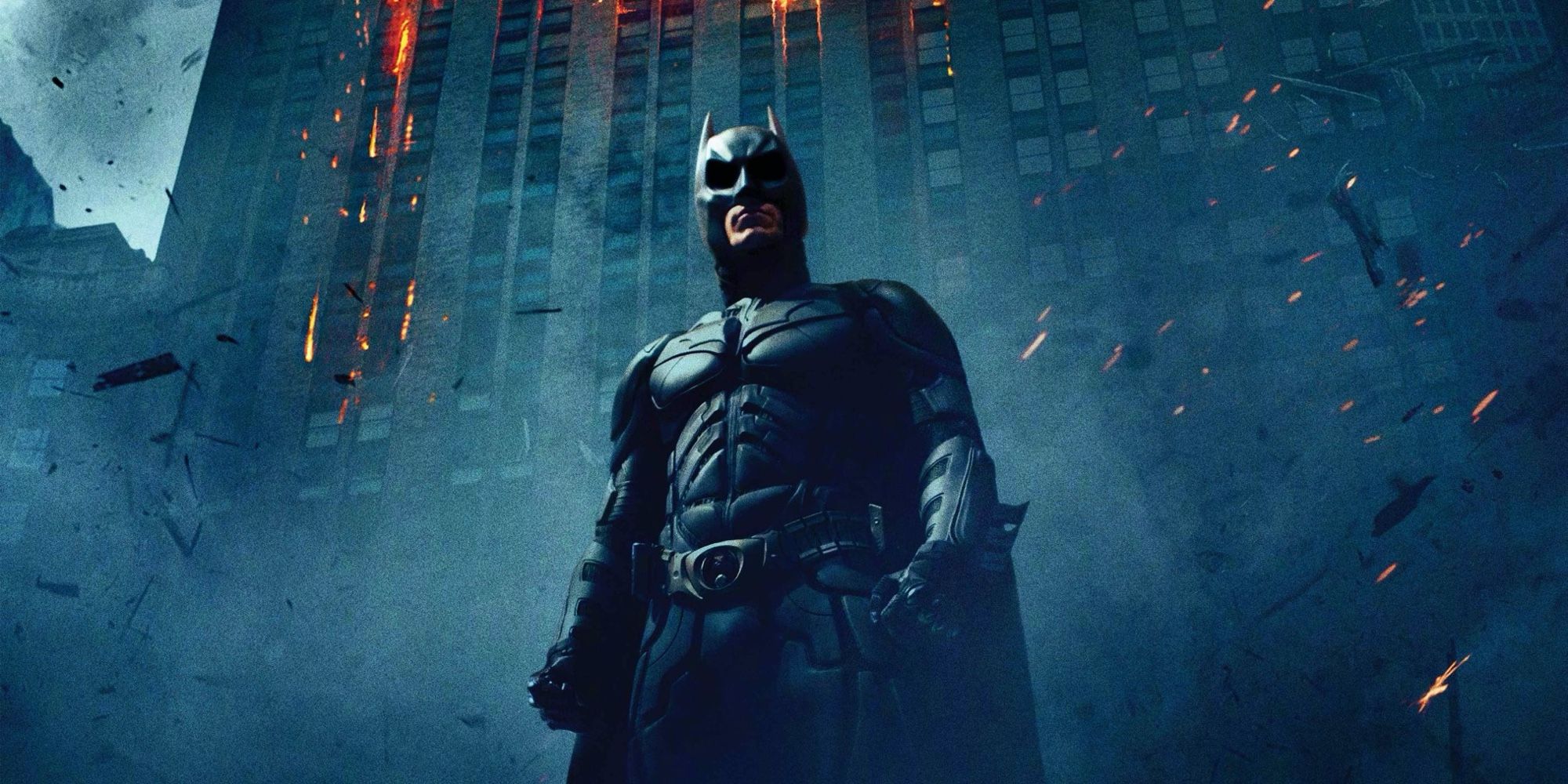 Batman stands in front of a dark building in The Dark Knight 