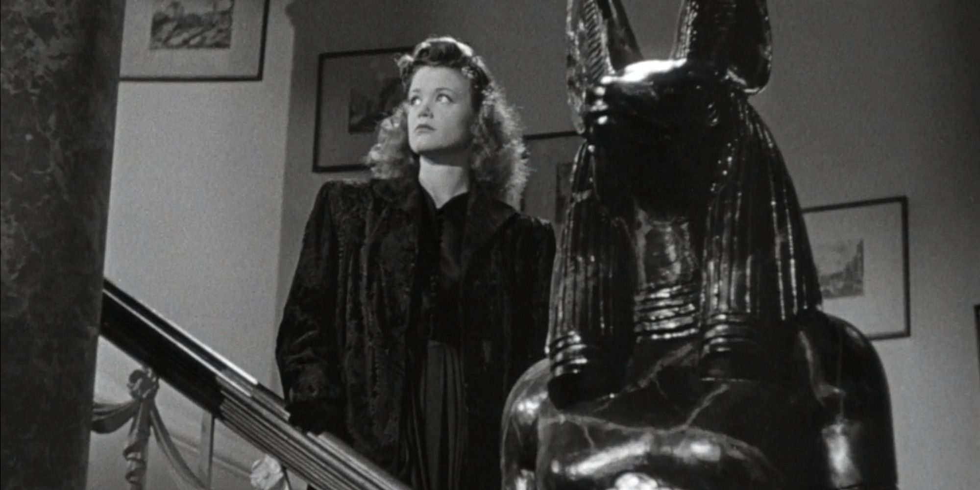 Irena standing by a anthopromorphic cat statue in Cat People (1942)