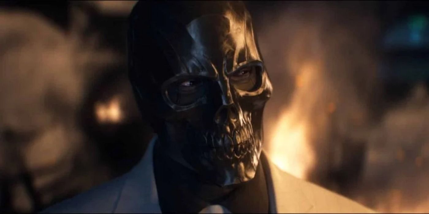 Black Mask standing in front of a fire