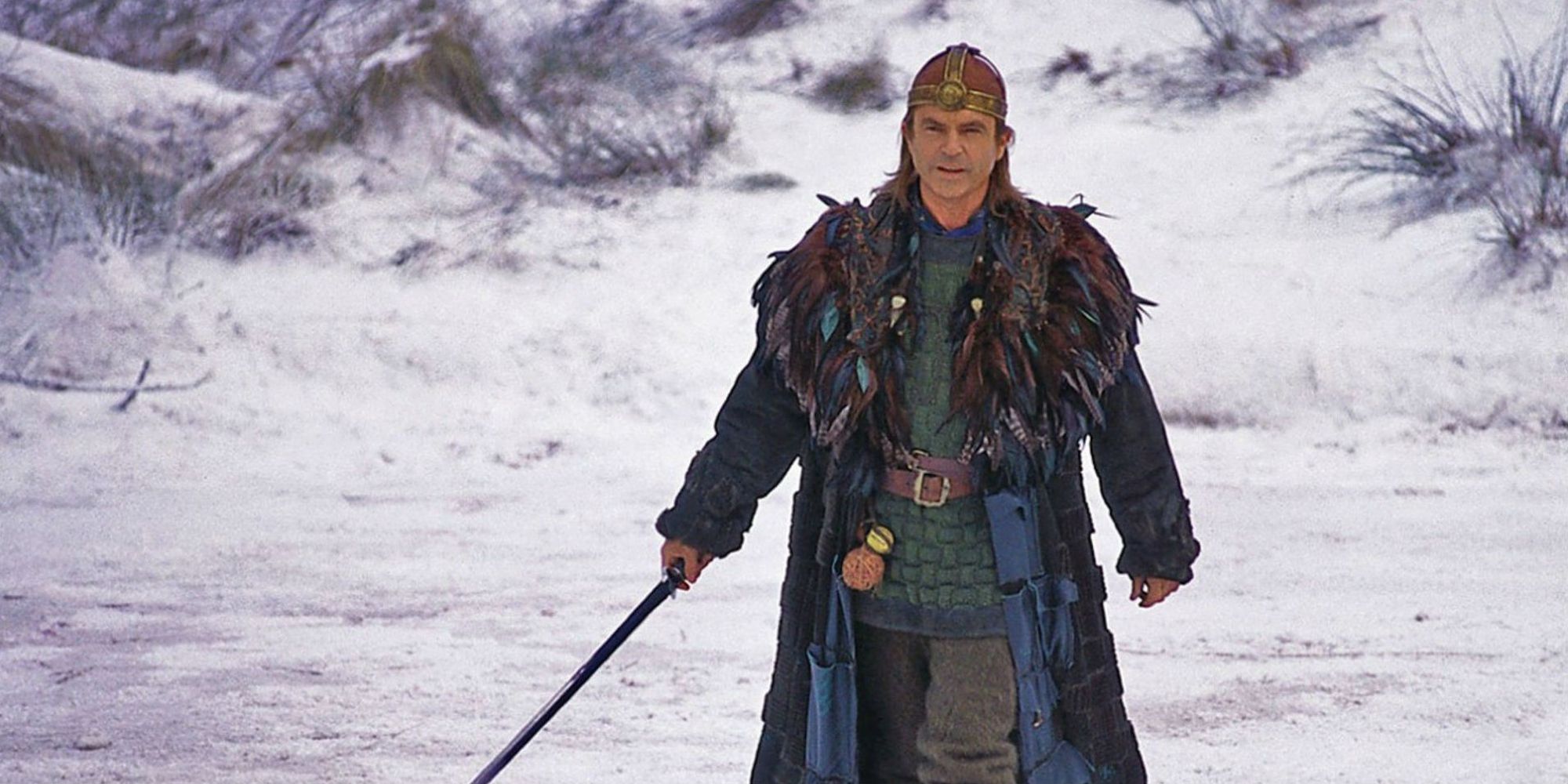Sam Neill with a sword in the snow in the 1998 fantasy film Merlin.