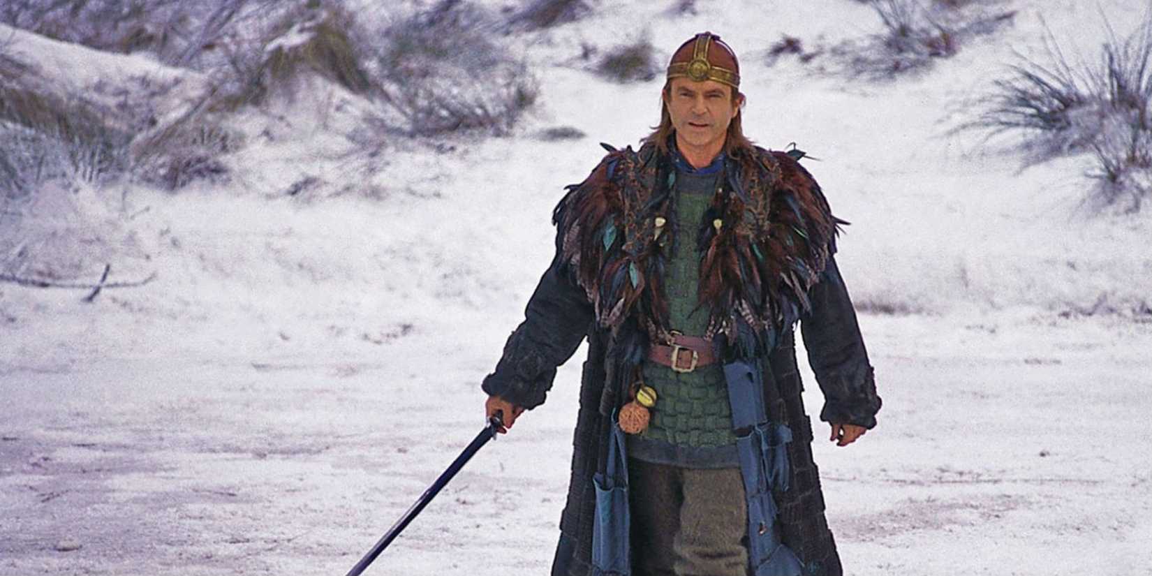Sam Neill with a sword in the snow in the 1998 fantasy film Merlin.