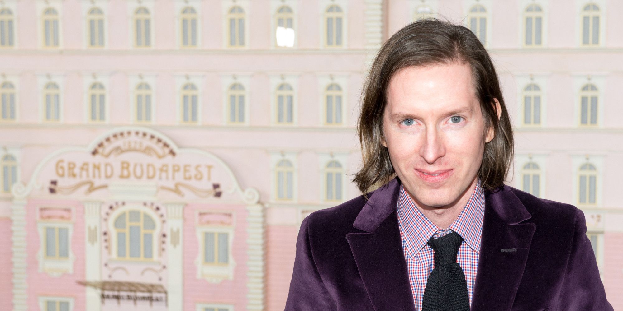 Wes Anderson standing in front of the model of the Grand Budapest Hotel