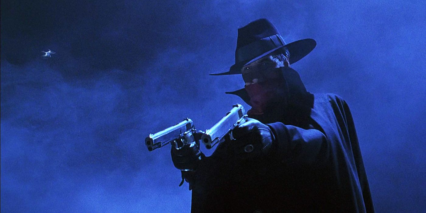 Alec Baldwin as The Shadow aiming two pistols surrounded by fog in The Shadow