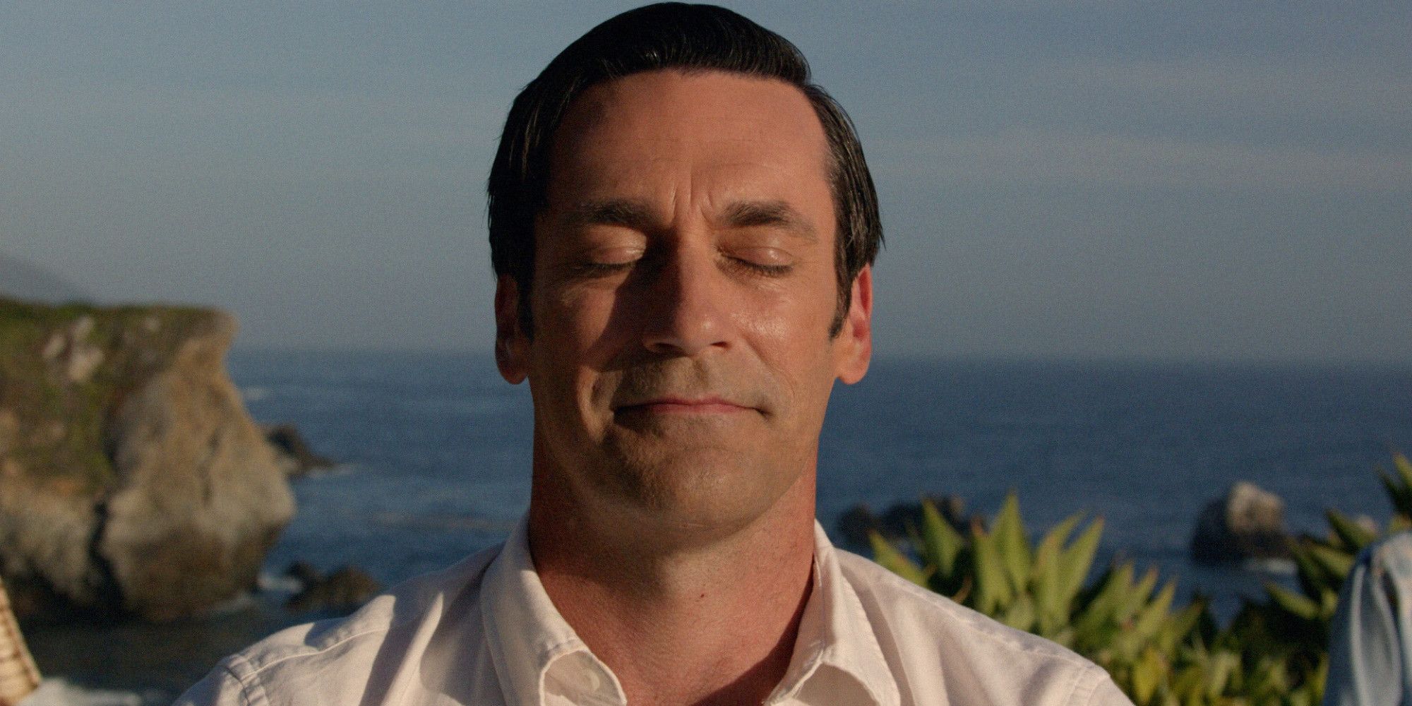 Jon Hamm as Don Draper smiling while meditating in Mad Men Finale