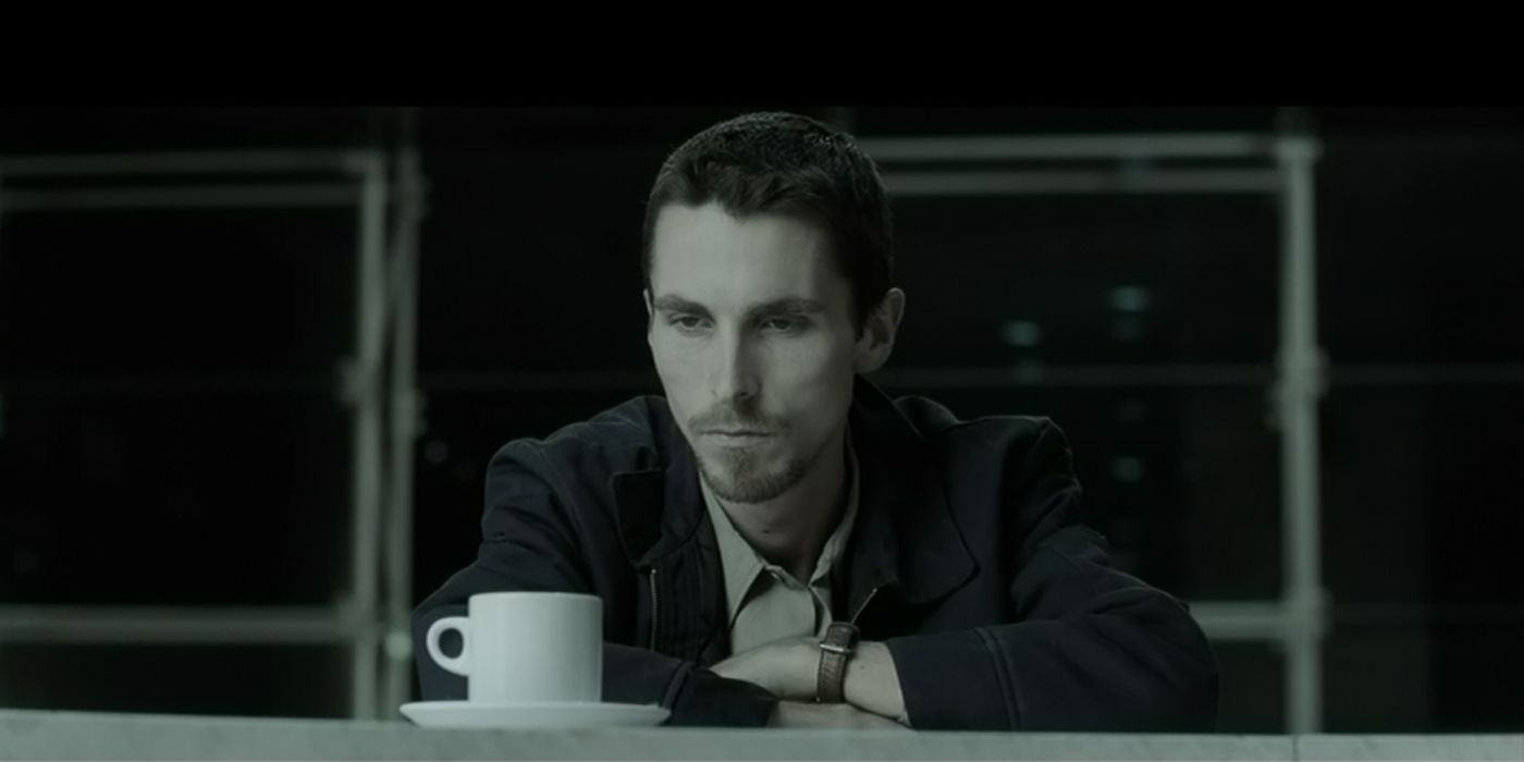 Christian Bale assis devant une tasse dans The Machinist