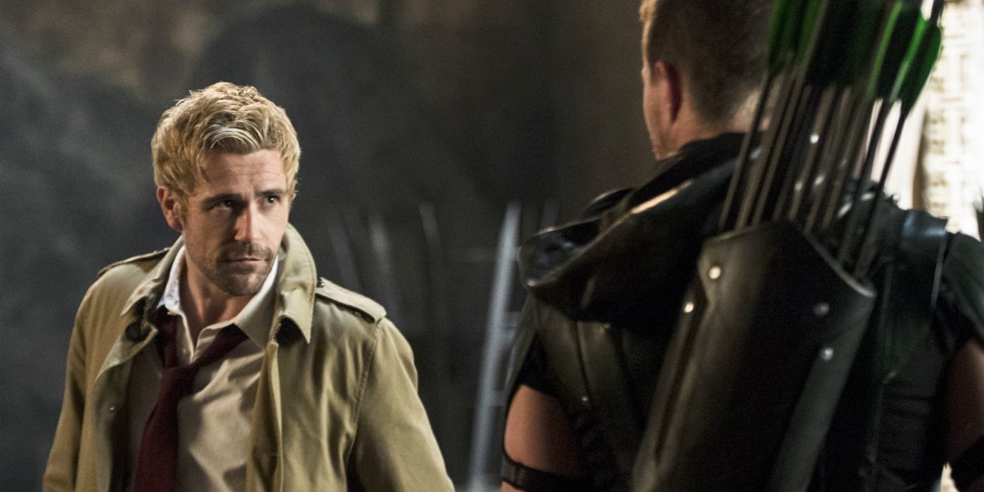 John Constantine, wearing his signature brown coat, staring down Oliver Queen in his Green Arrow costume