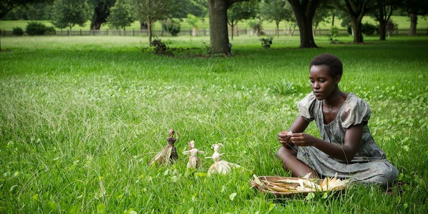 Lupita Nyong'o sitting in a field in 12 Years A Slave