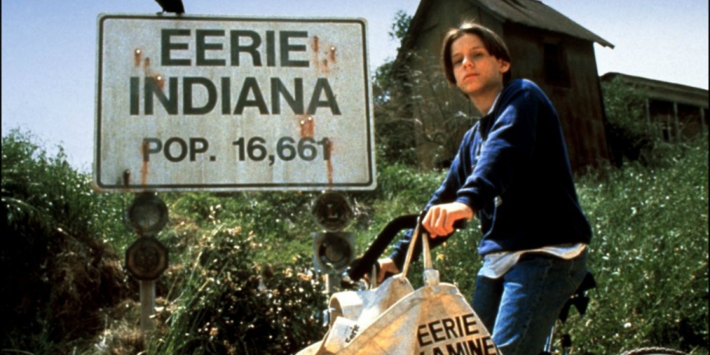 A kid parks his bike in front of the Eerie Indiana sign 