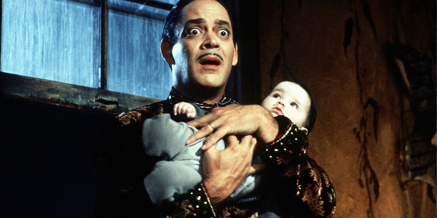 Raul Julia segura um bebê em Addams Family Values