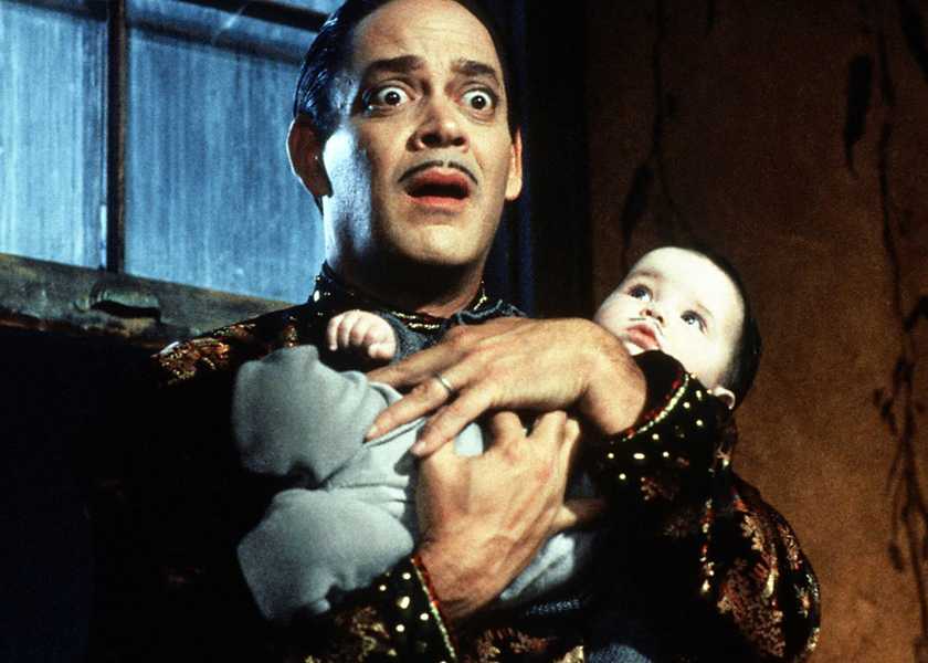 Raul Julia holds a baby in Addams Family Values