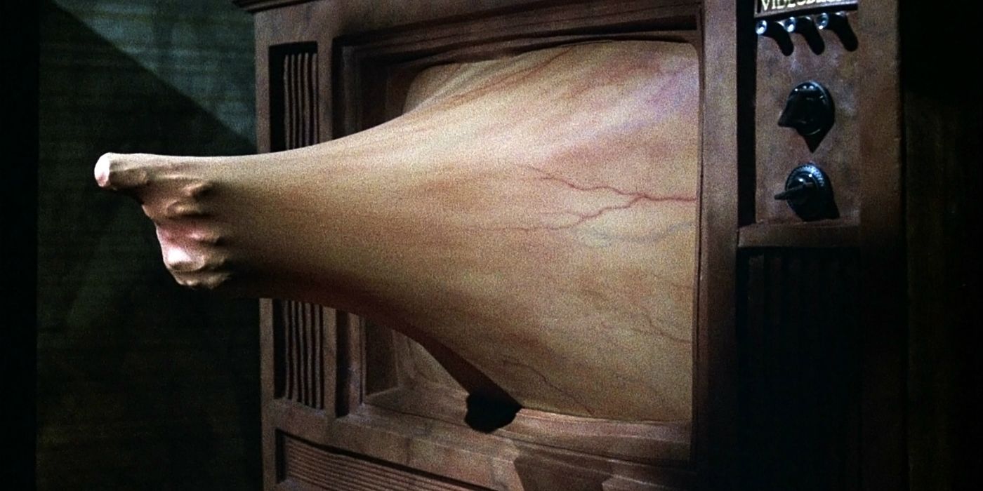 An arm pointing a gun oozes out of a TV in Videodrome