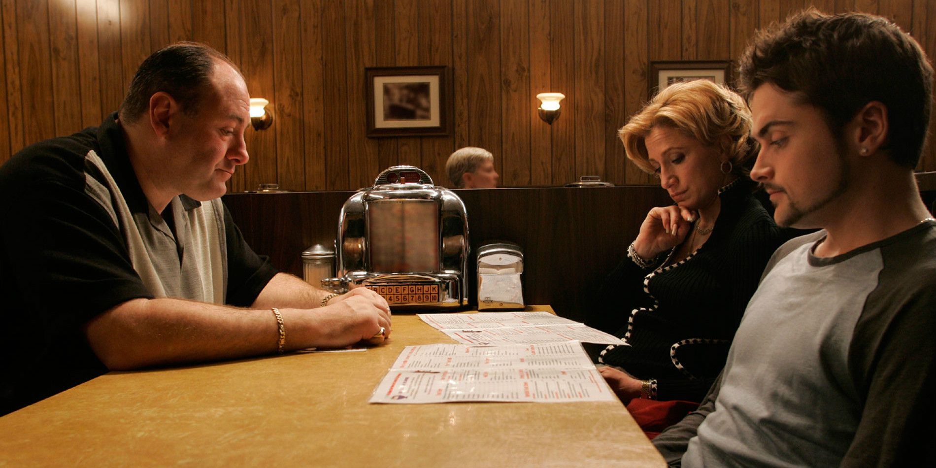 Tony, Carmela e AJ sentados em uma mesa de jantar em Os Sopranos