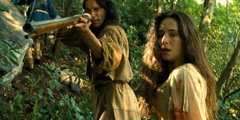 Daniel Day-Lewis aiming a rifle beside Madeline Stowe in The Last of the Mohicans