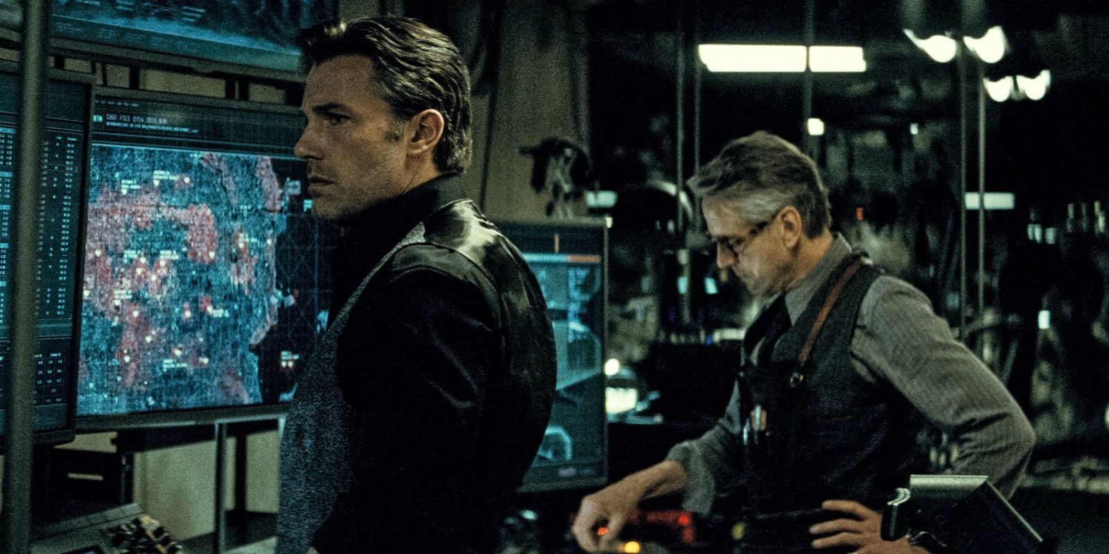 Bruce Wayne and Alfred Pennyworth standing by the monitors in the Batcave in Batman v Superman