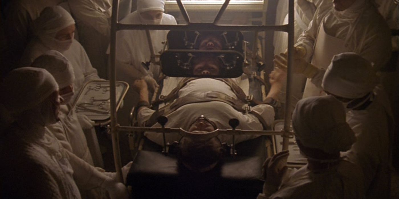 Tim Robbins' Jacob strapped to a bed surrounded by monstrous doctors in Jacobs Ladder