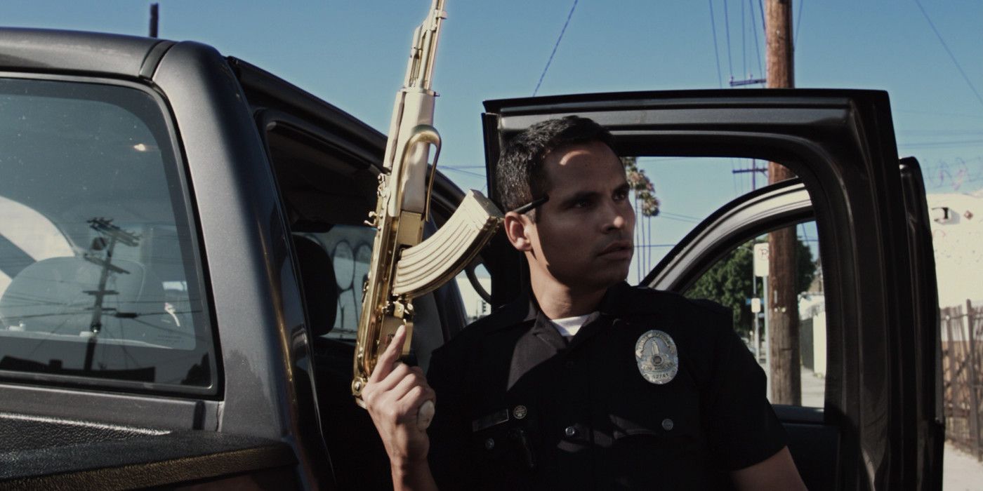 Michael Pena in a police uniform holding a golden gun in End of Watch