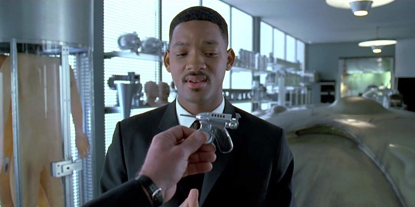 Will Smith as Agent J looking down at the noisy cricket weapon in Men in Black