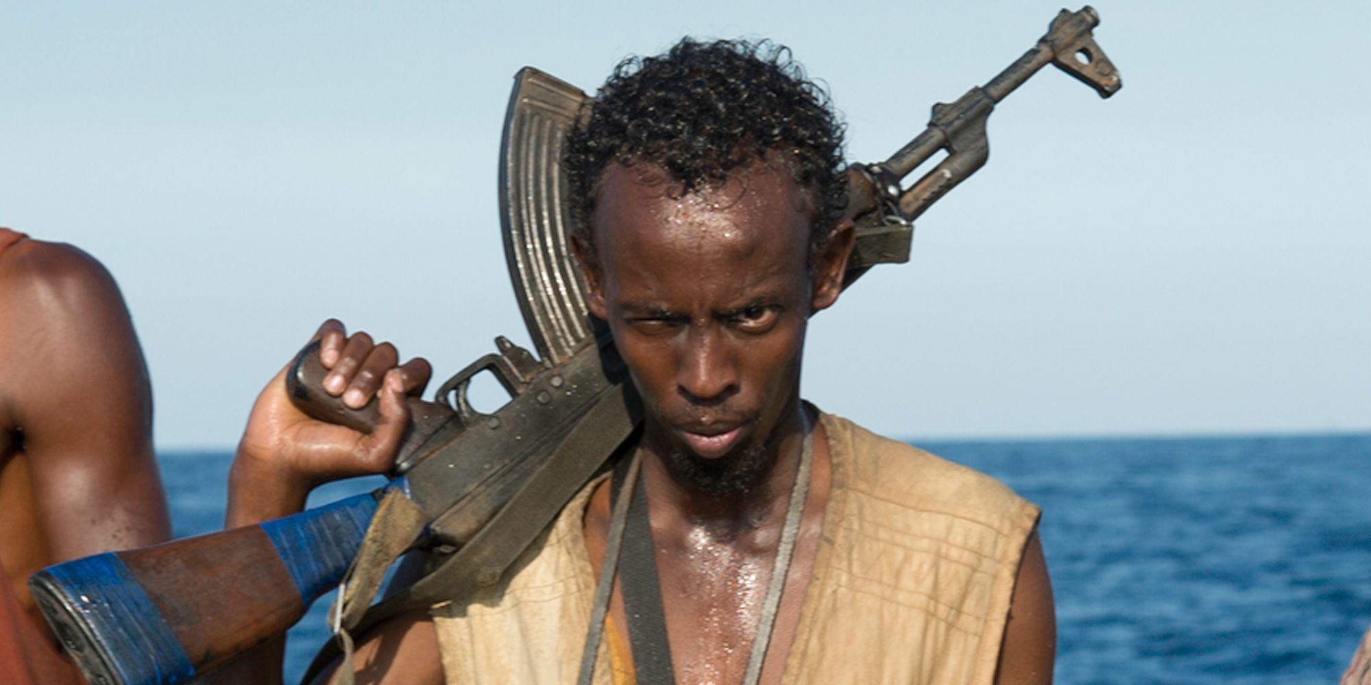 Barkhad Abdi dalam kostum Captain Phillips memegang AK-47