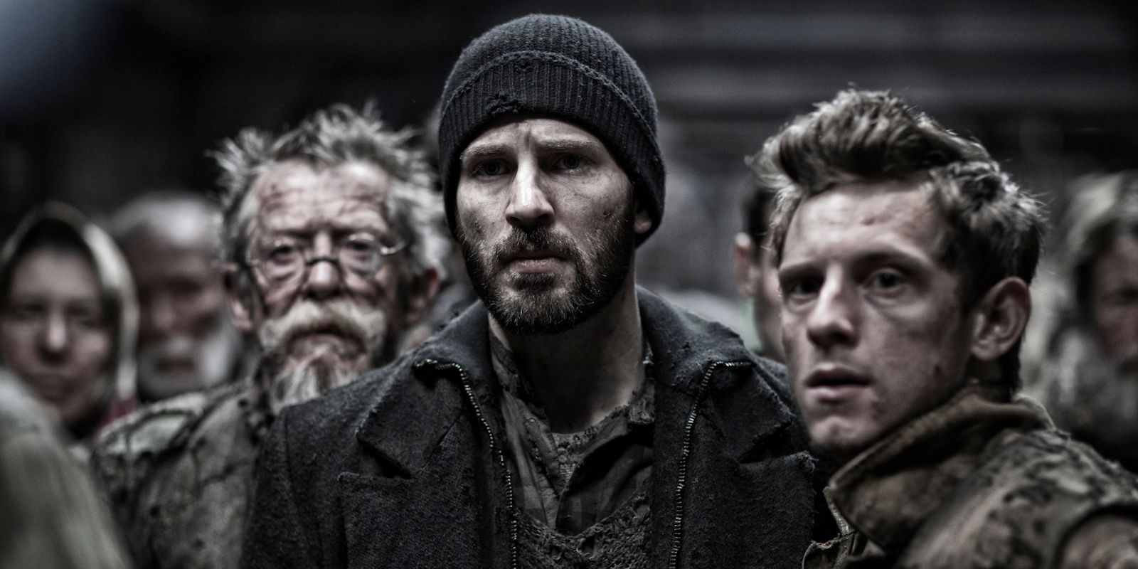 Chris Evans and Jamie Bell amidst other people looking at something in Snowpiercer 2013