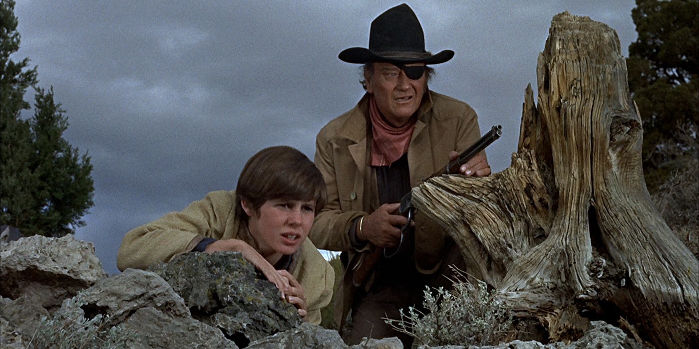 John Wayne holds a gun as Rooster Cogburn in True Grit