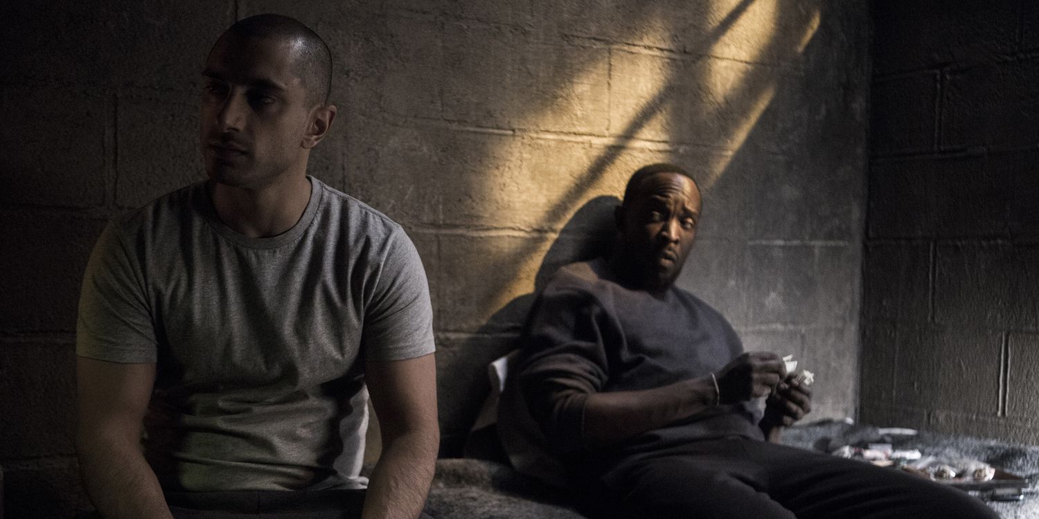 Michael K. Williams and Riz Ahmed sitting on a prison cell bed in The Night Of