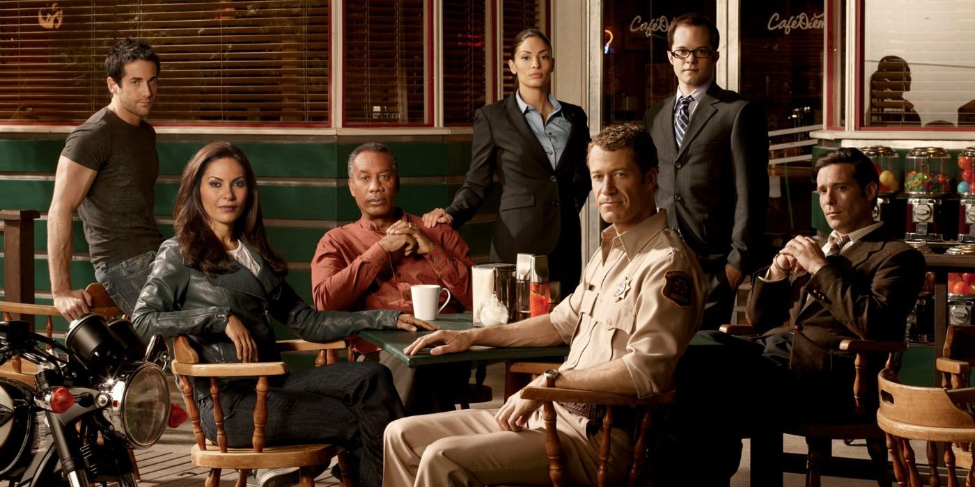 The cast of Eureka posing around a table outside for a promotional photo