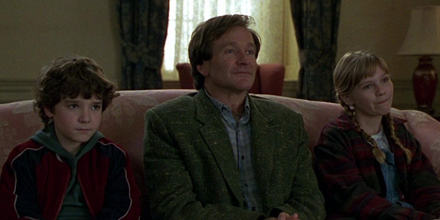 Peter (Bradley Pierce), Alan (Robin Williams), and Judy (Kirsten Dunst) sit on a couch in Jumanji (1995)