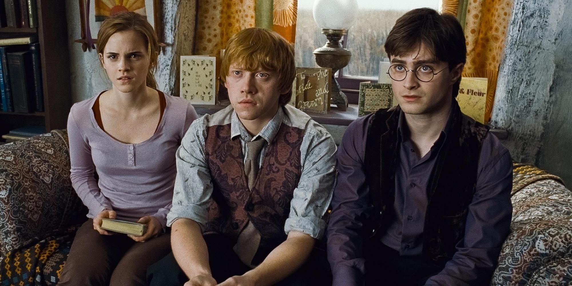Harry, Ron e Hermione sentados juntos e parecendo confusos em Harry Potter e as Relíquias da Morte Parte 1.