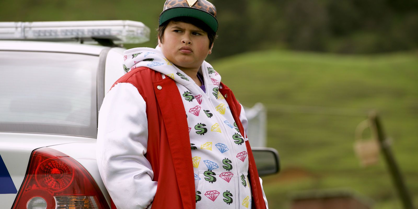 Ricky Baker leaning against a car and turning to his right in Hunt for the Wilderpeople