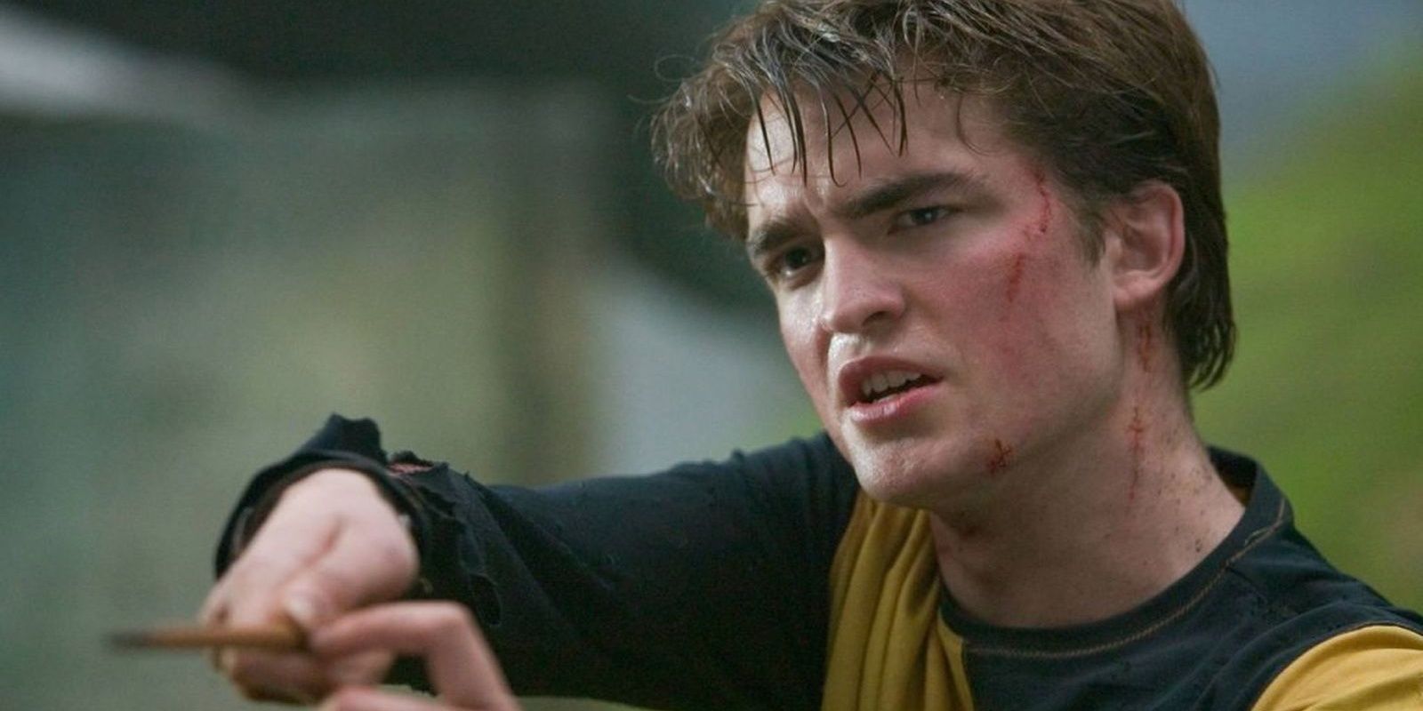 Cedric Diggory (Robert Pattinson) holds up his wand with cuts on his face in Harry Potter and the Goblet of Fire