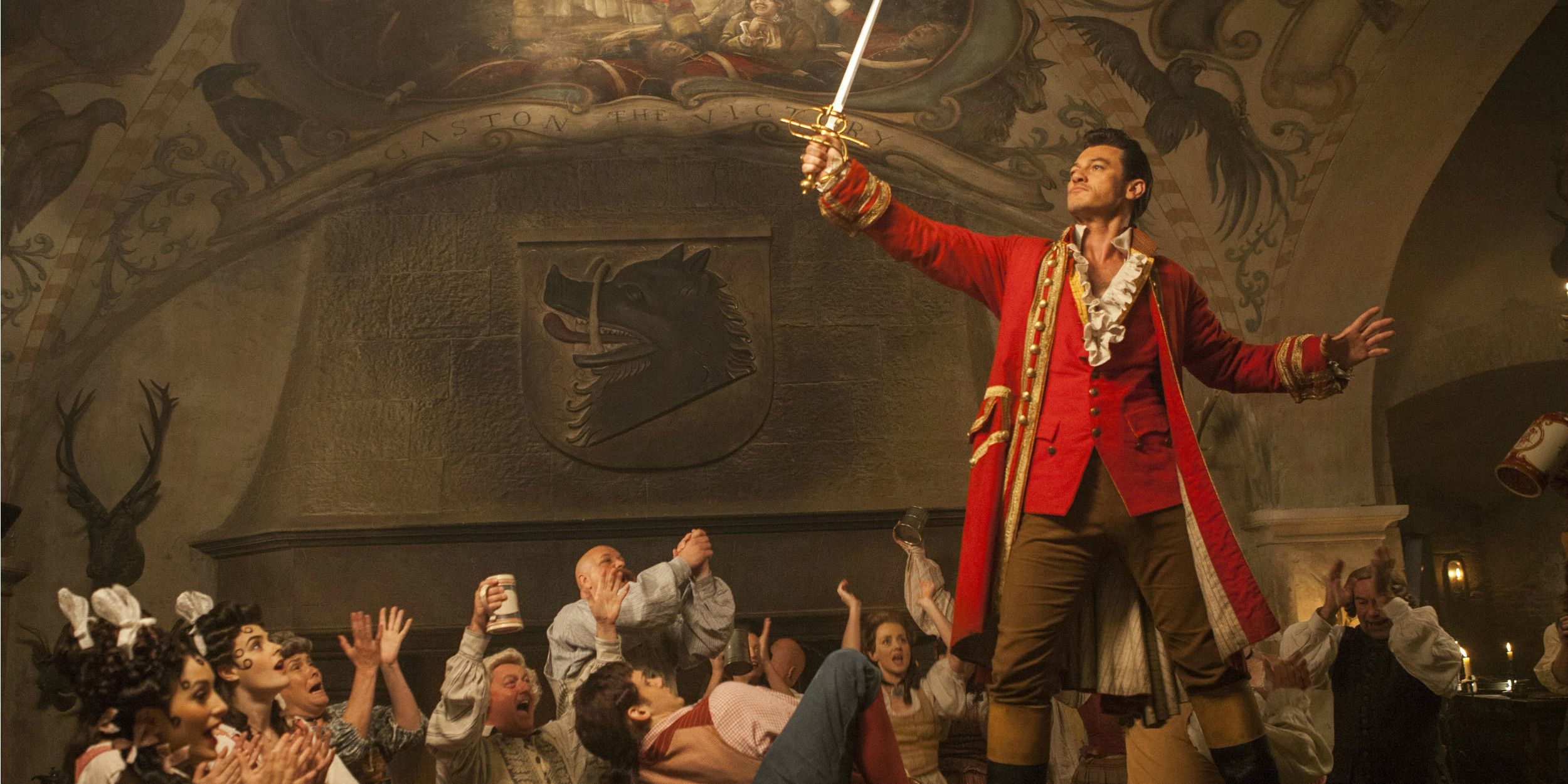 Gaston (Luke Evans) holds up a sword to an adoring tavern crowd in Beauty and the Beast