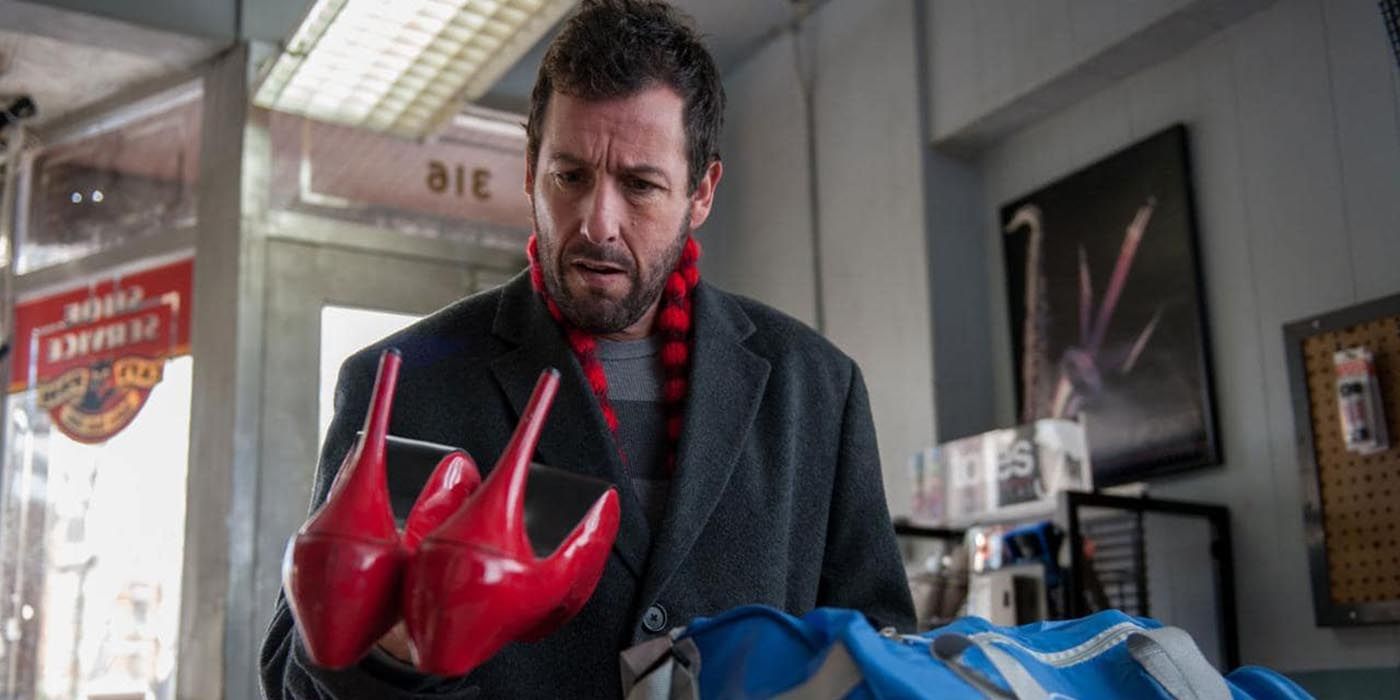 Adam Sandler holds up red shoes in The Cobbler