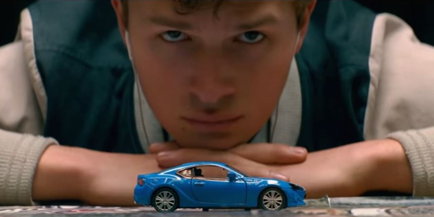 Baby Driver looking at a miniature car