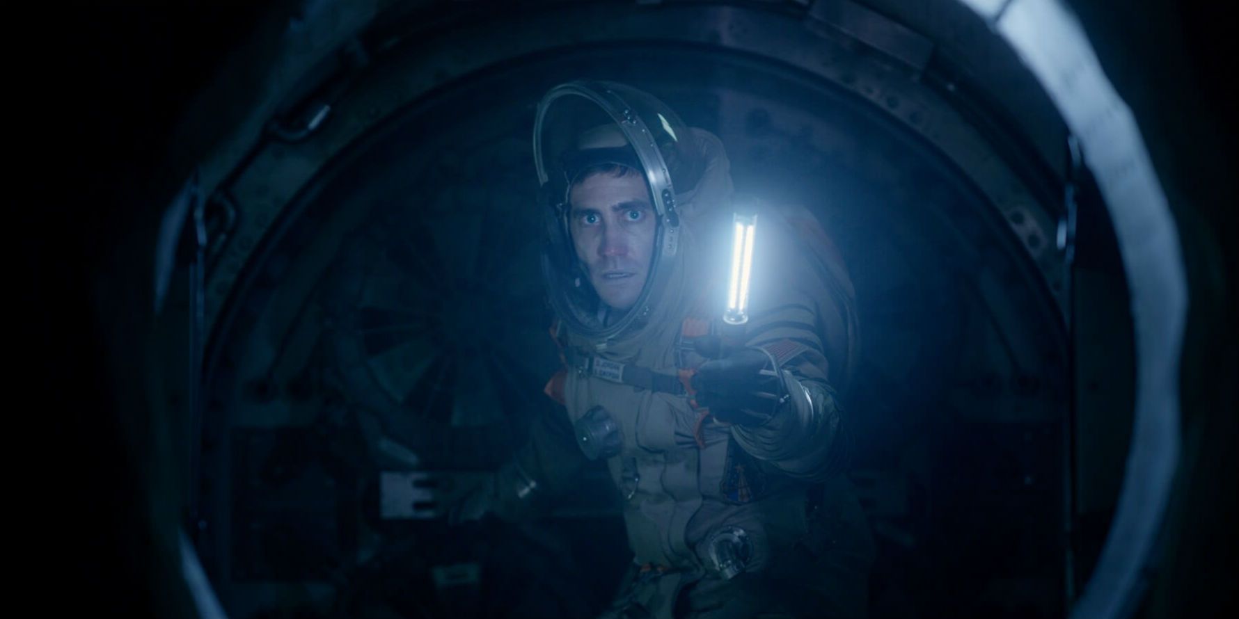 Jake Gyllenhaal in a space suit shining a light in Life