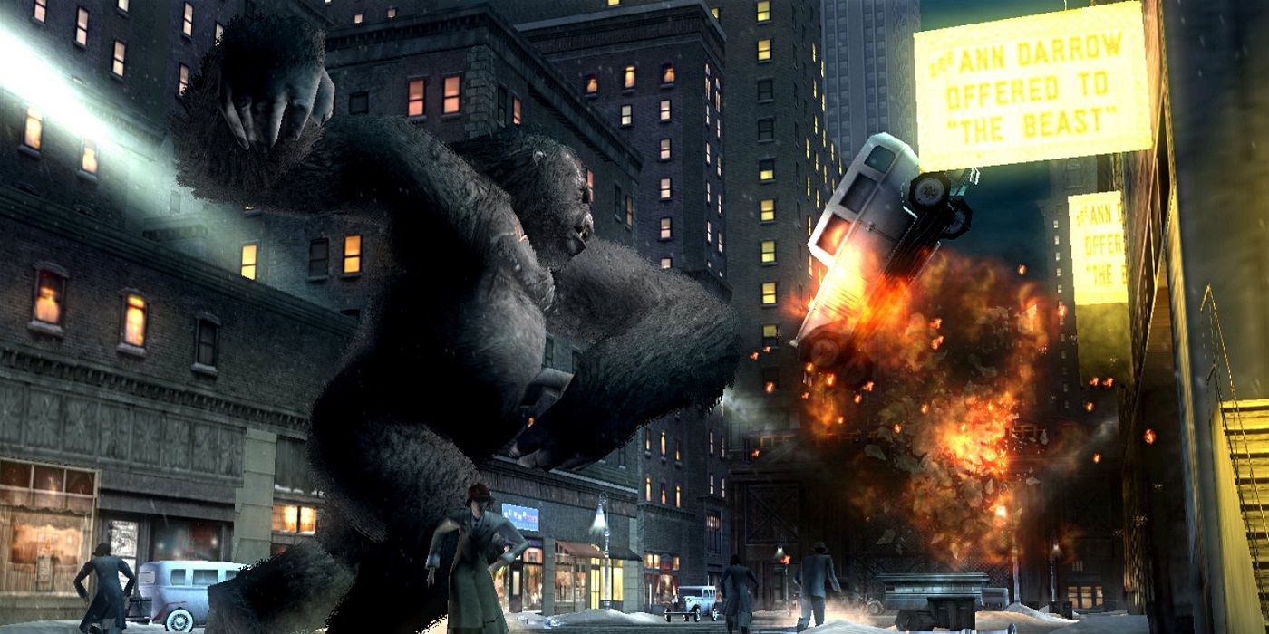 King Kong video game screenshot showing Kong stomping along a city street next to buildings, car blowing up in front of him