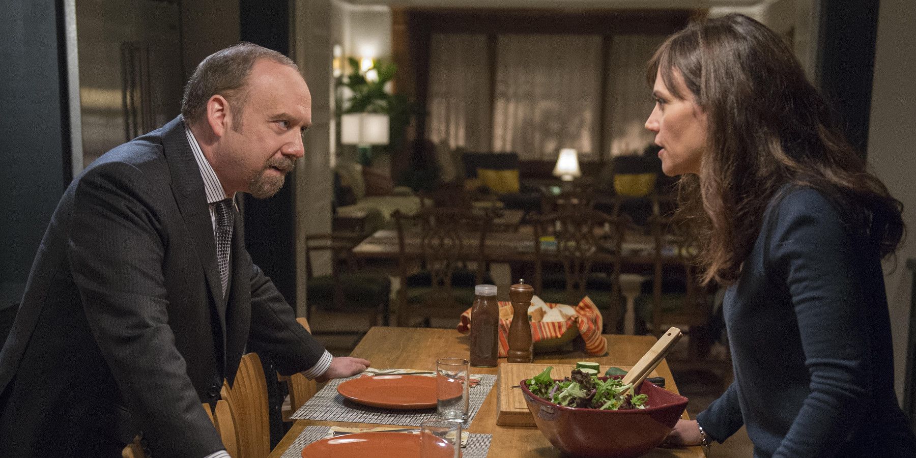 Wendy and Chuck from Billions look at one another from across the table at home.