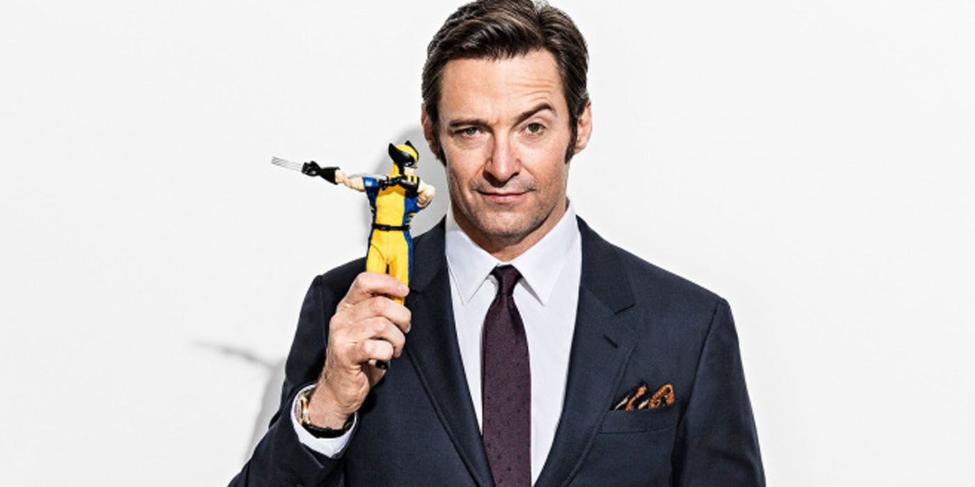Hugh Jackman raising an eyebrow holding a Wolverine action figure for Logan