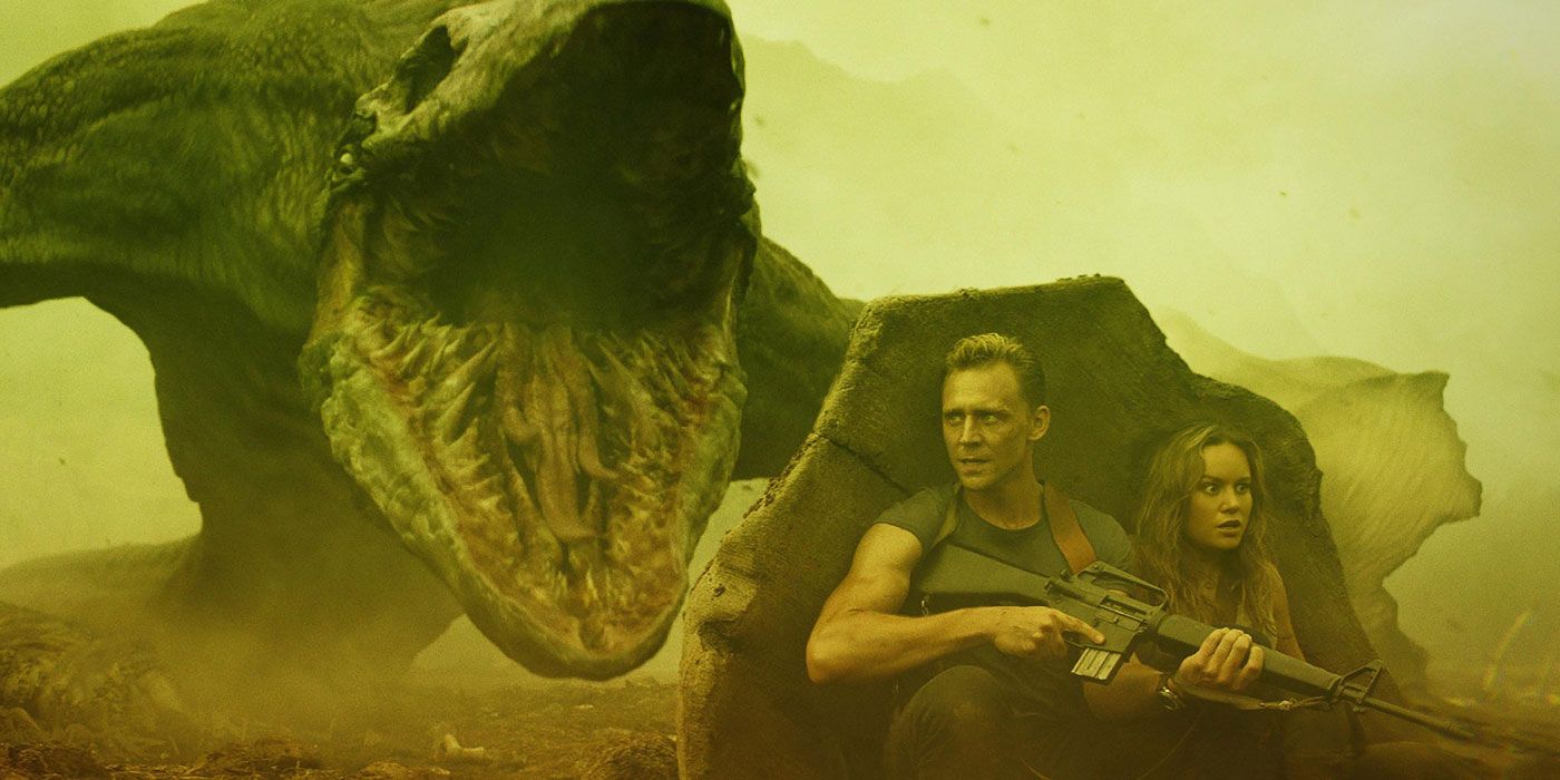 Tom Hiddleston and Brie Larson hide behind a rock from a skull crawler monster