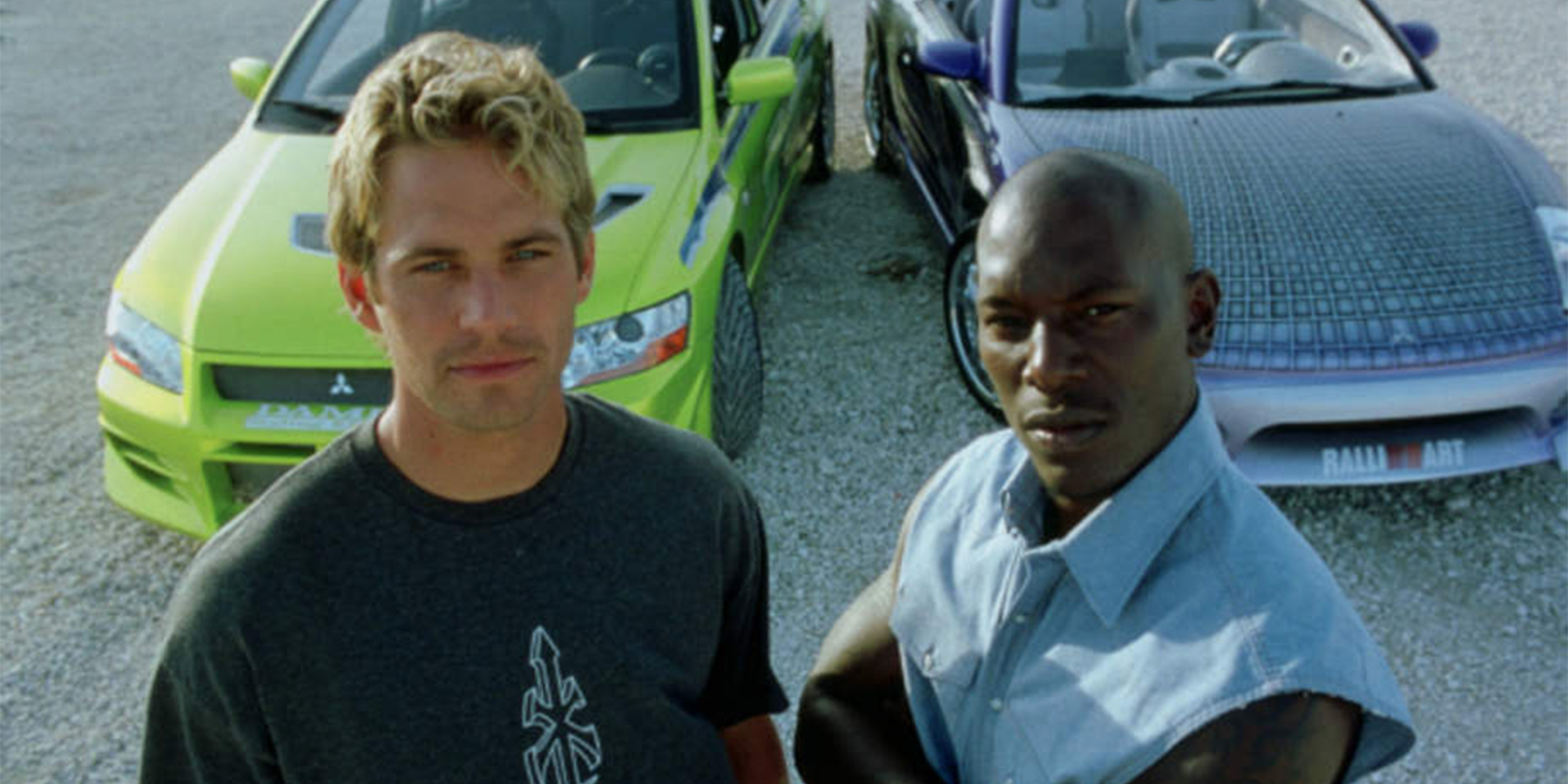 Brian and Roman pose in front of two cars in 2 Fast 2 Furious