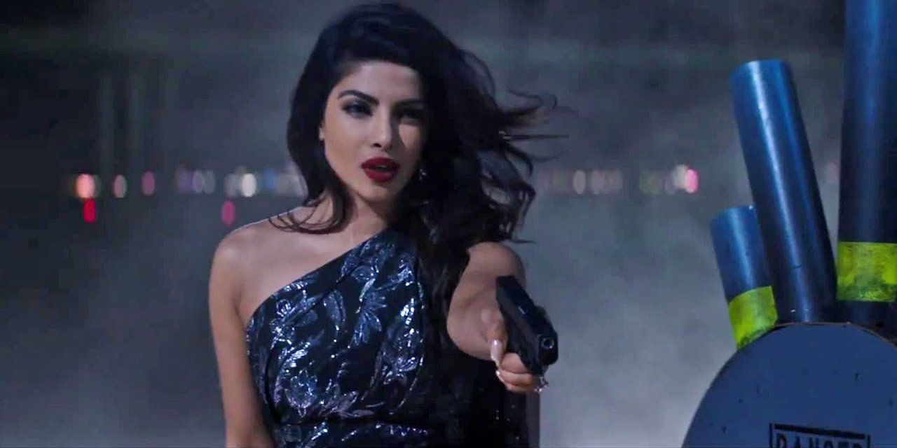 Priyanka Chopra in Baywatch holds a gun in a ball gown.