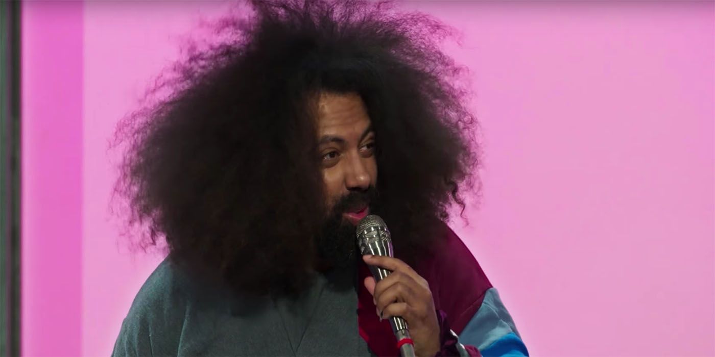 Reggie Watts in Spatial holding a microphone and looking off stage