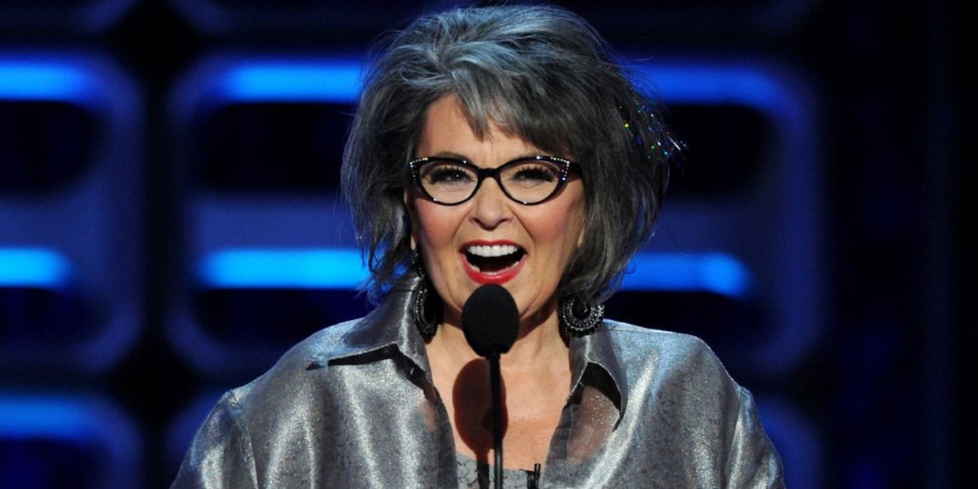Roseanne Barr standing in front of a microphone smiling