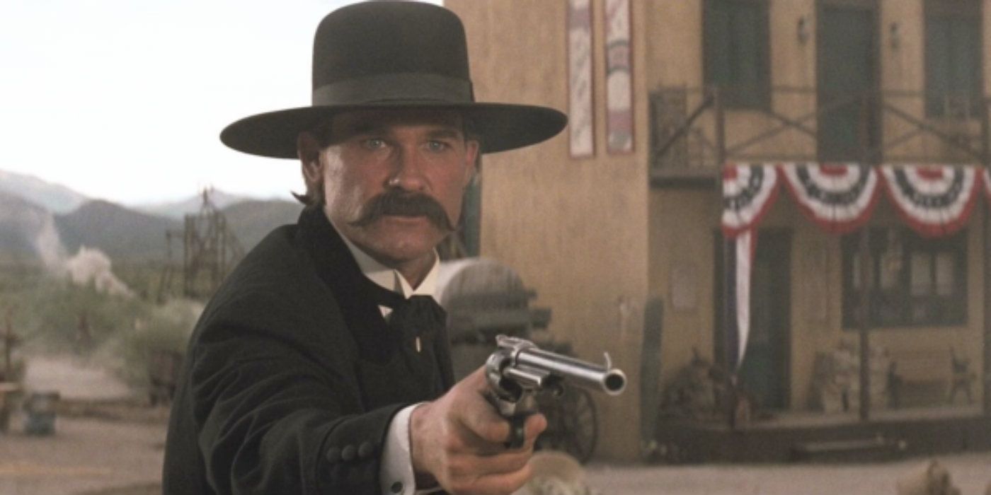 Kurt Russell como Wyatt Earp sosteniendo una pistola en una lápida