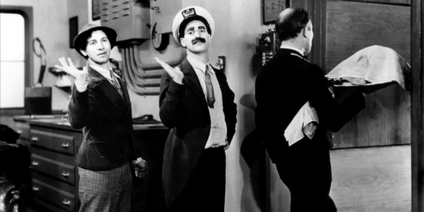 chico and groucho dancing behind a man carrying a platter in monkey business