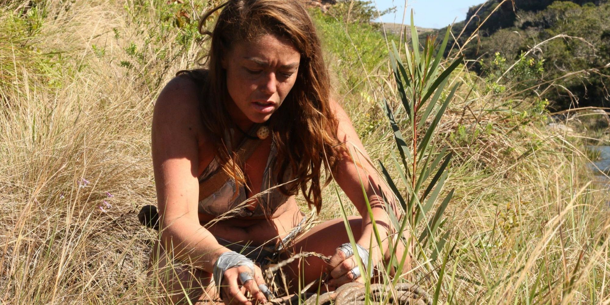 A woman in dry grass on Naked and Afraid