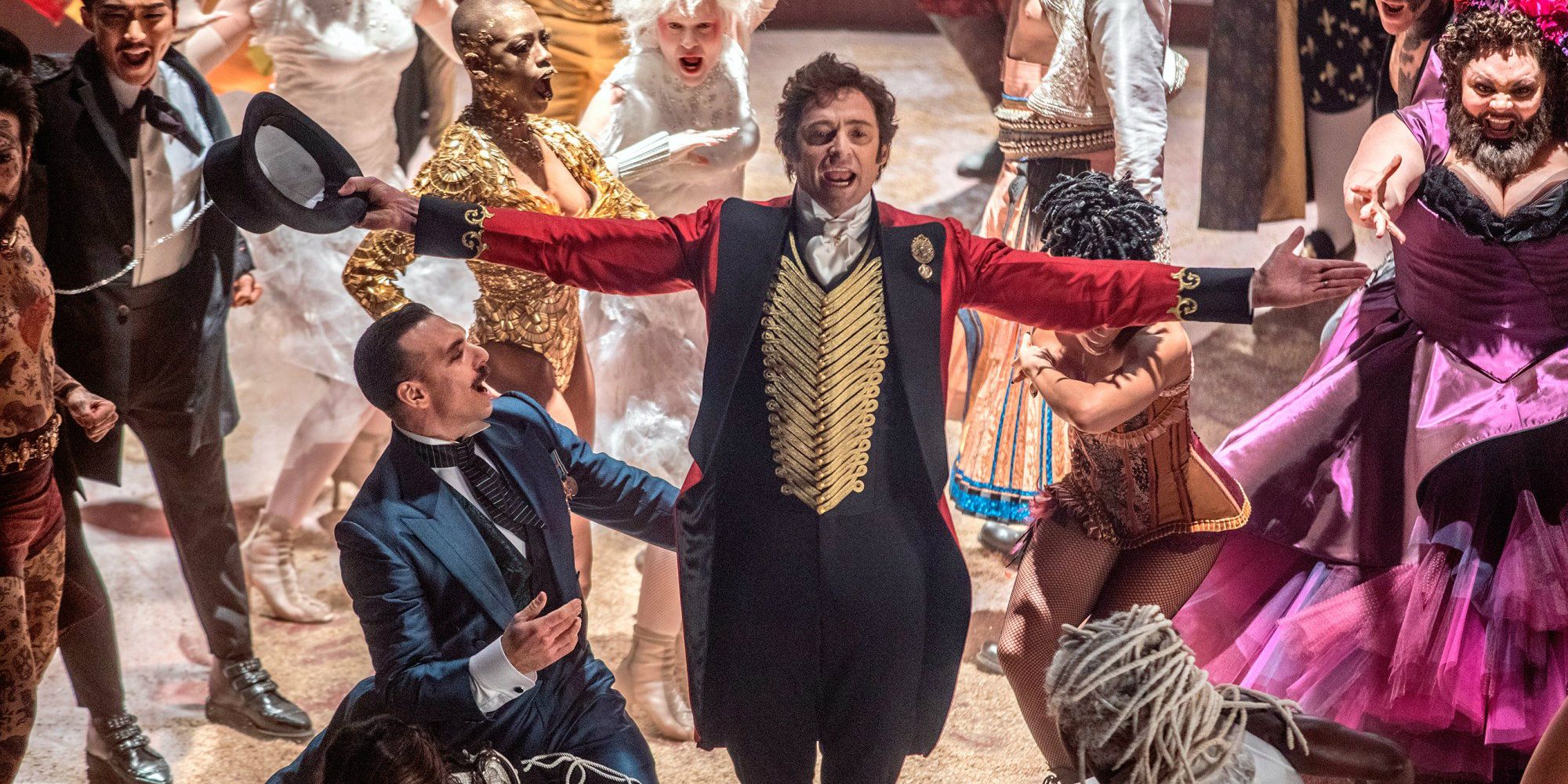 Hugh Jackman as PT Barnum posing amid the members of the circus in The Greatest Showman