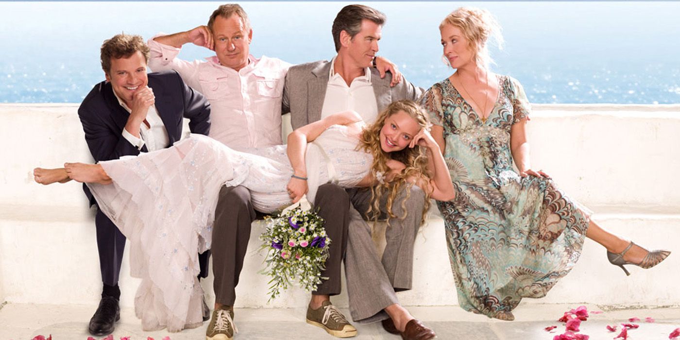 Bill, Harry, and Sam holding Sophie while looking at Donna in Mamma Mia promotional artwork