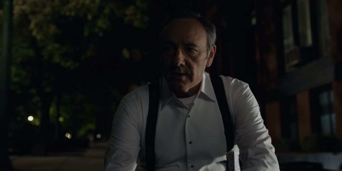 Frank Underwood talks to the camera while kneeling on the street in House of Cards