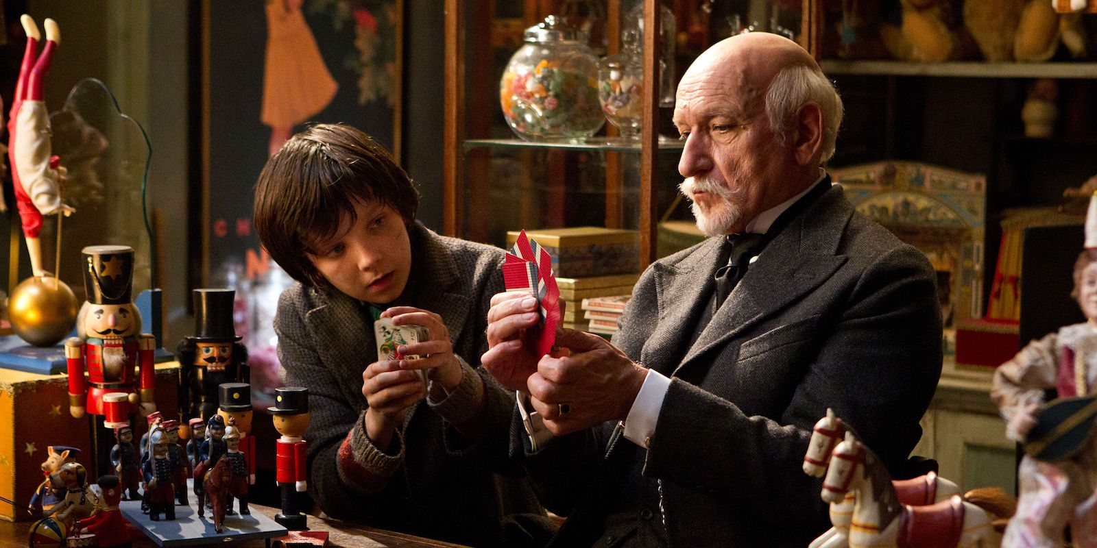 Asa Butterfield looking at Ben Kingsley holding something in Hugo